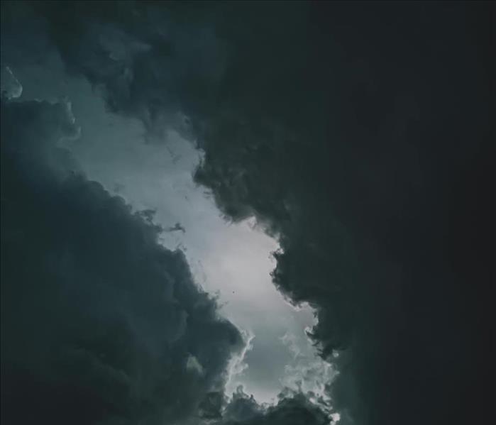 A dramatic image of dark storm clouds with a faint light breaking through the center, symbolizing an approaching winter storm